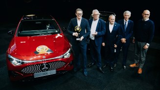
Links im Bild steht ein elektrischer Mercedes-Benz CLA in MANUFAKTUR patagonienrot metallic mit einem &bdquo;Car of the Year&ldquo;-Aufkleber auf der Motorhaube. Rechts daneben stehen mehrere Vertreter von Mercedes-Benz, die die Auszeichnung bei der Preisverleihung entgegengenommen haben und pr�sentieren.
