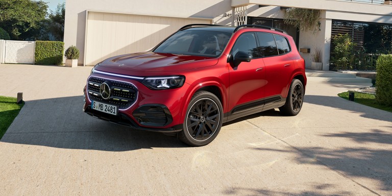 
				Der neue GLB mit Hybrid-Technologie in MANUFAKTUR patagonienrot metallic steht geparkt vor einer beigefarbenen Garage. Im Hintergrund sieht man neben der Garage rechts einen Hauseingang. Das Fahrzeug ist aus einer leicht schr�gen Frontperspektive zu sehen.
				