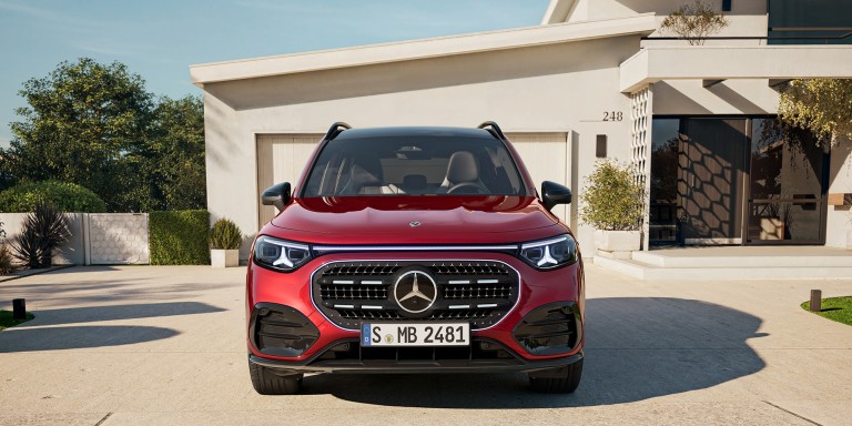 
				Der neue GLB mit Hybrid-Technologie in MANUFAKTUR patagonienrot metallic steht vor einer beigefarbenen Garage in einer Einfahrt. Das Fahrzeug ist frontal zu sehen. Im Hintergrund sind B�ume und ein Hauseingang.
				