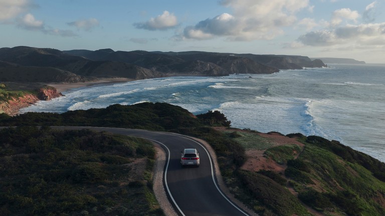 
			Luftaufnahme eines elektrischen GLC auf einer kurvigen K�stenstra�e mit Blick auf Meer, Wellen und Felsk�ste.
		