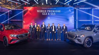 
Weltpremiere des neuen Mercedes-Benz GLE und des neuen Mercedes-Benz GLS am 31. M�rz im Werk Tuscaloosa, Alabama: Mehrere Personen stehen auf der B�hne zwischen beiden Fahrzeugen vor einer gro�en Veranstaltungsleinwand.
