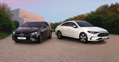 
					  Links steht eine schwarze Mercedes-Benz A-Klasse, rechts ein wei�er Mercedes-Benz CLA, aufgenommen auf einem gepflasterten Vorplatz vor moderner Architektur und B�umen.
					  