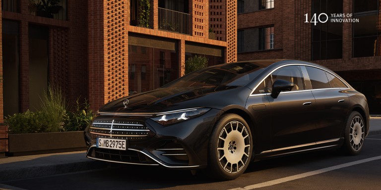 
					Ein schwarzer Mercedes-Benz EQS f�hrt auf einer Stra�e vor einem Backsteingeb�ude in der Abendsonne.
				 