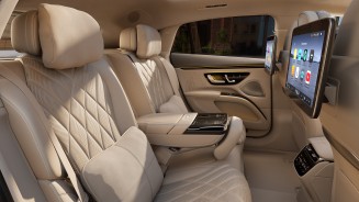 
Das Fond des Mercedes-Benz EQS aus der seitlichen Perspektive mit edel verzierten Sitzen in Beige. Auf der rechten Seite sind zwei gro�e Displays zu sehen.
