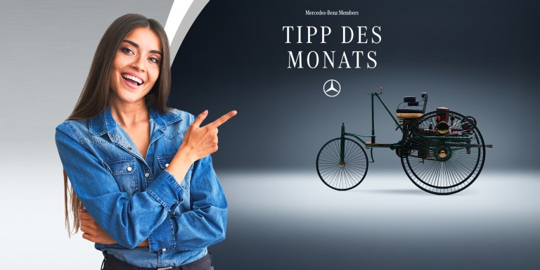 
				Eine br�nette Frau auf der linken Seite deutet mit dem Zeigefinger in die andere Bildh�lfte. Dort ist in einer Studioaufnahme die linke Seitenansicht einer authentischen Nachfertigung des Patent-Motorwagens von Carl Benz aus dem Jahr 1886 zu sehen. In der oberen H�lfte des Bildes steht &bdquo;Mercedes-Benz Members Tipp des Monats&ldquo;, darunter ist der Mercedes-Stern abgebildet.
				