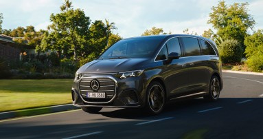 
					  Der Mercedes-Benz VLE in obsidianschwarz metallic f�hrt auf einer leicht geschwungenen Stra�e an G�rten, B�umen und Wohnh�usern vorbei.
					  