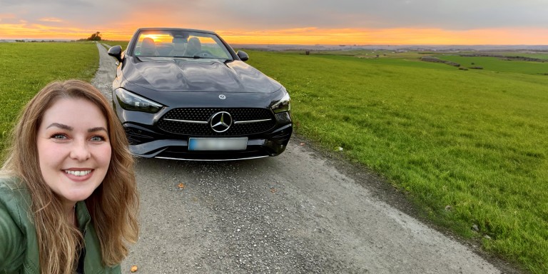 
				Mercedes-Benz Members Kundin Irina Felline steht vor ihrem schwarzen CLE Cabriolet, das auf einem Feldweg umgeben von einer grnen Landschaft steht.
				
