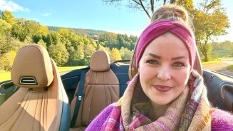 
Mercedes-Benz Members Kundin Irina Felline sitzt am Steuer ihres CLE Cabriolets, im Hintergrund sind herbstliche Bume und ein blauer Himmel zu sehen.

