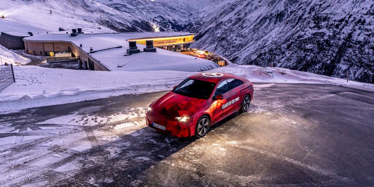 
				Der neue CLA, als rot getarnter Erlknig, parkt inmitten einer verschneiten Alpenlandschaft.
				