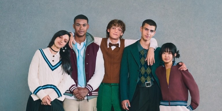 
				Fnf junge Studenten mit US-amerikanischem Erscheinungsbild stehen vor einer trkisen Wand dicht beieinander und lcheln.
				