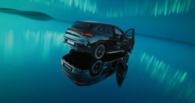 
						  Ein schwarzer EQE SUV steht auf einer spiegelnden Oberflche unter Polarlichtern.
						  