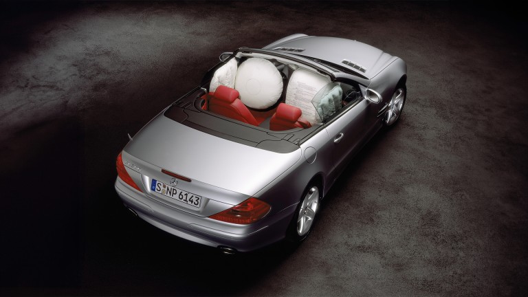 
			Blick von hinten auf ein Mercedes-Benz SL 500 Cabriolet in Silber mit roten Sitzen, bei dem Fahrer- und Beifahrer-Airbags sowie Head-/Thorax-Seitenairbags entfaltet sind.
		