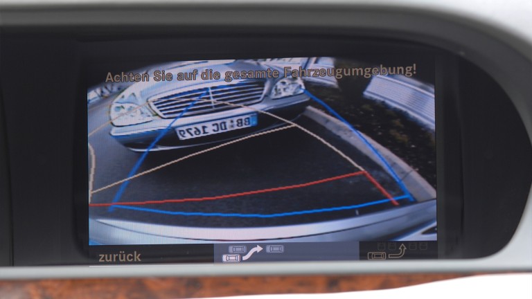 
			Nahaufnahme des Displays im Cockpit, auf dem das Bild der Rckfahrkamera mit farbigen Hilfslinien sowie ein anderes Mercedes-Benz Fahrzeug zu erkennen sind, vor dem gerade eingeparkt wird.
		
