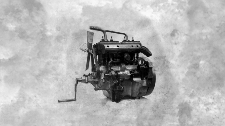 
			Abbildung eines Mercedes 8/18 PS Motors mit Anlasserkurbel vor einem grau-weien Hintergrund.
		
