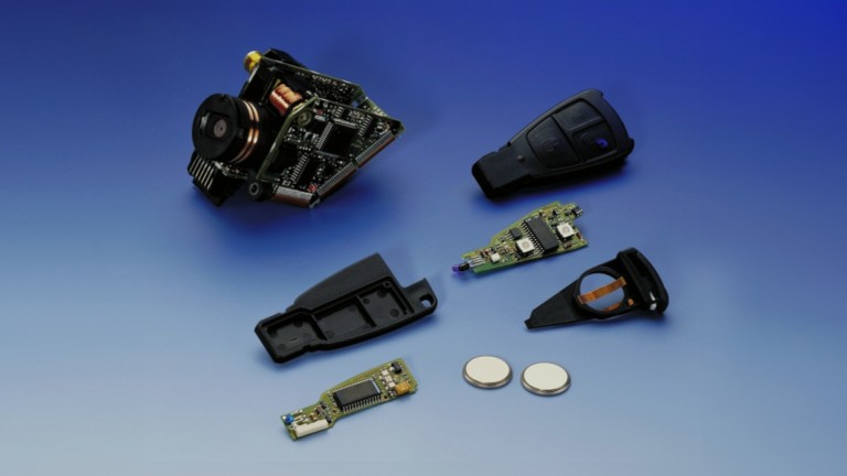
			Die Einzelteile eines auseinandergebauten Schlssels der C-Klasse Baureihe 202 inklusive Mikro-Elektronik liegen verteilt auf einem blauen Untergrund.
		