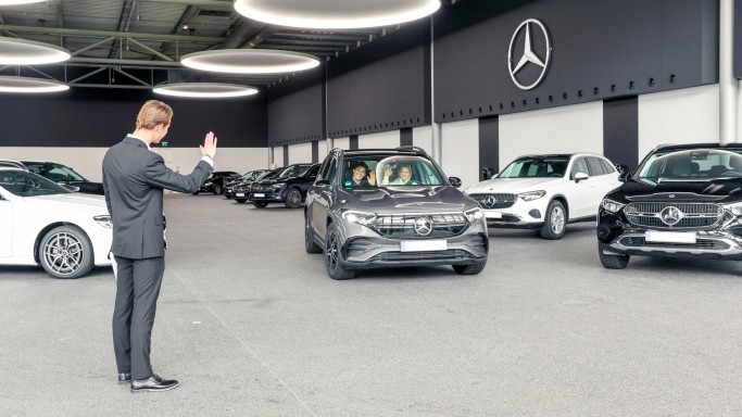 
				Kundendienstmitarbeiter Jonathan Vielhaber verabschiedet Mercedes-Benz Members Kundin Lena Celine Breimeier in ihrem neuen EQB.
				