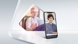 
Eine Grafik mit grauem Hintergrund. In der Mitte ist ein Mann an einem Tablet zu sehen, davor steht ein Smartphone, auf dem eine Frau mit Headset abgebildet ist.
