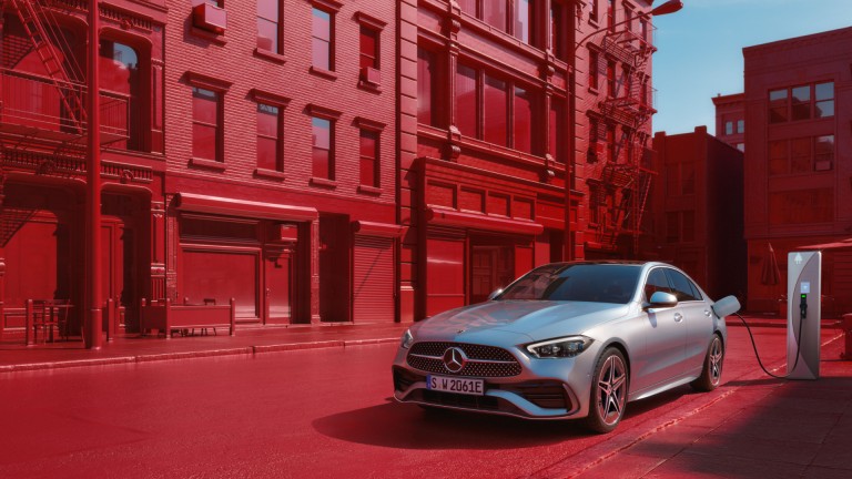 
			Eine C-Klasse Limousine als Plug-in-Hybrid in mojavesilber ldt an einer Ladesule auf einem Parkplatz am Straenrand einer Innenstadt.
		