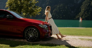 
						  Eine Frau lehnt sich an einen Mercedes-Benz und geniet die Sonne.
						  