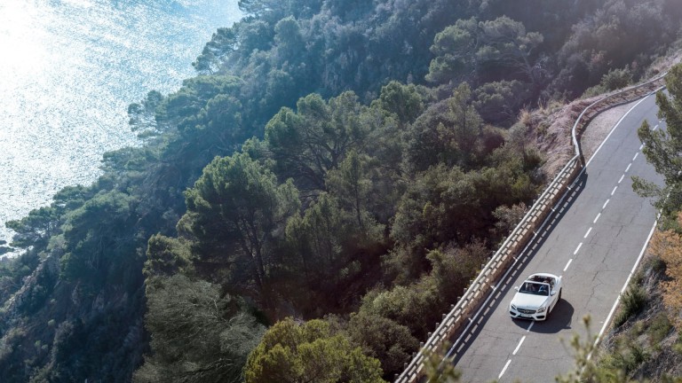 
			Blick von auen durch das Panoramadach eines  
EQS SUV von Mercedes-Benz. Eine Person sitzt auf der Rckbank, im Hintergrund ist der rtliche Himmel beim Sonnenuntergang zu sehen.
		