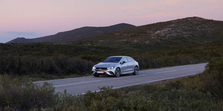 
				Ein Mercedes-Benz fhrt ber eine Strae, umgeben von grner Landschaft.
				