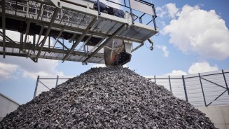 
Ein Magnetkran hebt Altmetall von einem groen Schrottberg.
