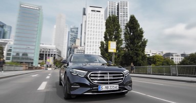 
						  Eine E-Klasse Plug-in-Hybridmodell in nautikblau fhrt auf einer Strae, im Hintergrund ist Frankfurts Skyline zu sehen.
						  