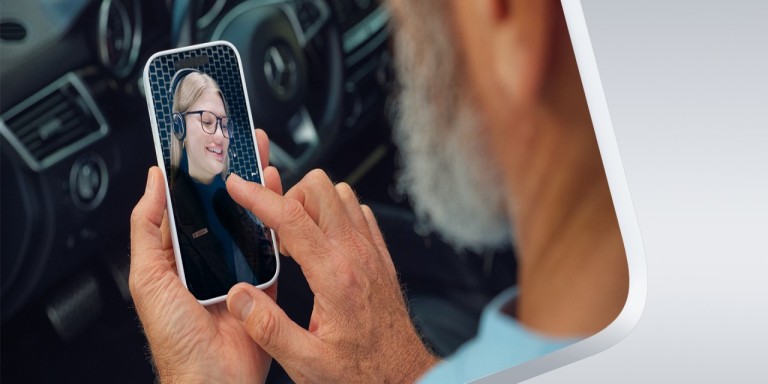 
				Ein Mann mit grauem Bart in einem Mercedes-Benz sitzend hlt ein Smartphone in der Hand. Auf dem Screen erkennen wir eine Beraterin von Mercedes-Benz Members.) 
				