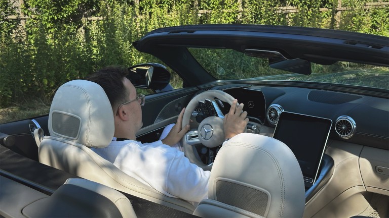
			Barrierefreiheit: Marlon Hontheim sitzt am Steuer seines silbernen Mercedes-AMG SL 43 Roadster, aufgenommen aus der Perspektive von rechts hinten.
		