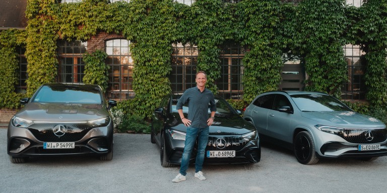 
				Moderator und Youtuber Matthias Malmedie steht vor einem mit Efeu bewachsenen Gebude, vor dem drei Mercedes-Benz Fahrzeuge geparkt sind. Von links nach rechts: ein EQA, eine Mercedes-AMG EQE Limousine und ein EQE SUV. 
				