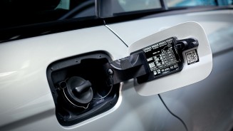 
Nahaufnahme einer geffneten Tankklappe eines Autos mit sichtbarem Tankdeckel und Betankungshinweisen im Inneren der Klappe.
