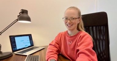 
						  Mercedes-Benz Members Mitarbeiterin Vera sitzt an ihrem Laptop und blickt lchelnd in die Kamera.
						  