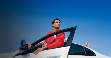 
						  Ein Mann in einem roten Hemd steigt in eine weies Mercedes-Benz Fahrzeug ein. Auf dem Fahrzeug sind an verschiedenen Stellen bunte Ostereier platziert.
						  
