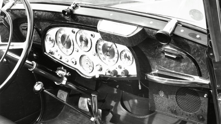 
			Schwarzwei-Aufnahme eines Armaturenbretts im Mercedes-Benz 770 aus dem Jahr 1937, mit einem Autoradio der Marke Telefunken und Senderskala als Rundinstrument.
		